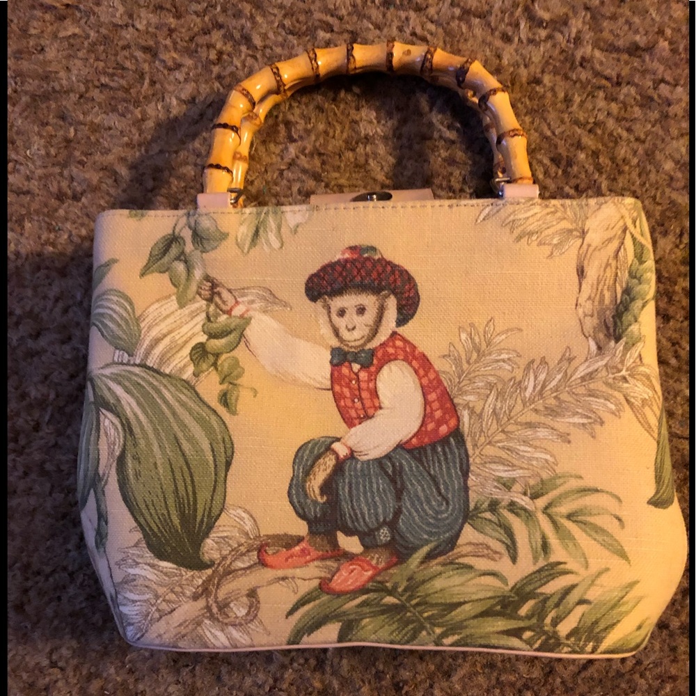 Multicolored bag with two cute posed monkeys on each side. Bamboo handles